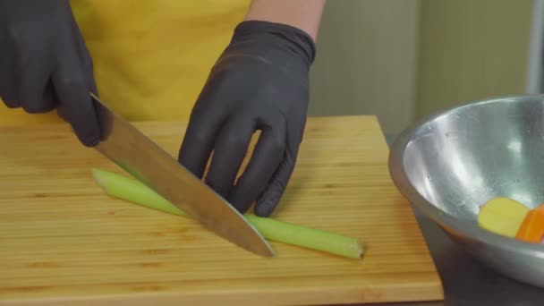 Chef szeletelés zeller szár a vágódeszka a konyhában, és helyezzük el a tálba — Stock videók