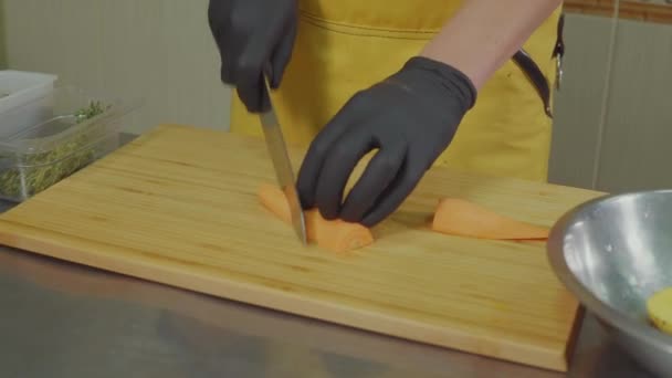 Cocinero profesional está cortando zanahoria cruda por piezas y lanzando en ensalada — Vídeos de Stock