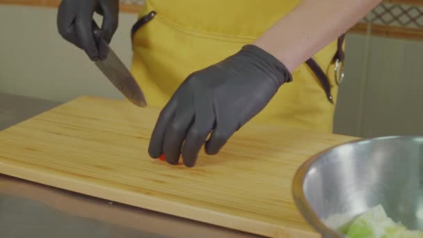 L'homme coupe les tomates cerises au couteau et les jette dans un bol avec de la salade — Video