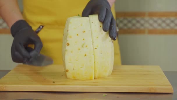 Professional male cook is slicing pineapple on pieces, close-up — Stock Video