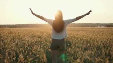 Gün batımı arka planda eller yükselterek genç kadının vücut üzerinde arka görünüm