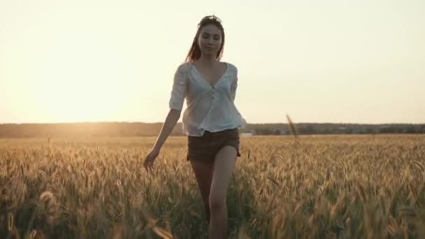 Очаровательная девушка прыгает в поле на рассвете, двигаясь к камере и оглядываясь вокруг — стоковое видео