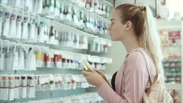 Joven artista mujer está examinando tubos con tintes en una tienda profesional — Vídeo de stock