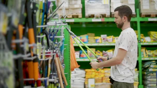 Adult man is watching and trying pruning shear in a hardware store — Stock Video