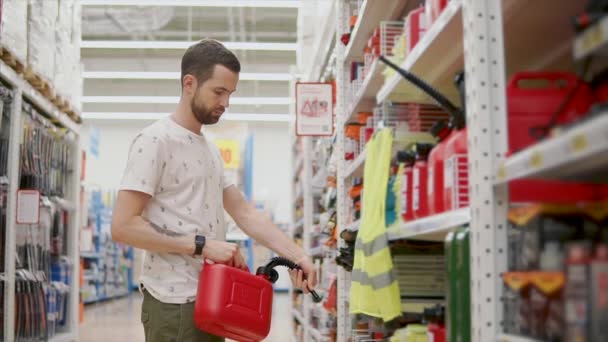 El hombre está aprendiendo un bote de plástico rojo para automóvil en una tienda — Vídeo de stock