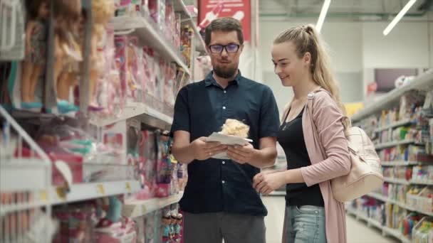 Togliatti Rusia - Junio 2018, Padres felices están de pie en una tienda de juguetes y examinando muñecas — Vídeos de Stock