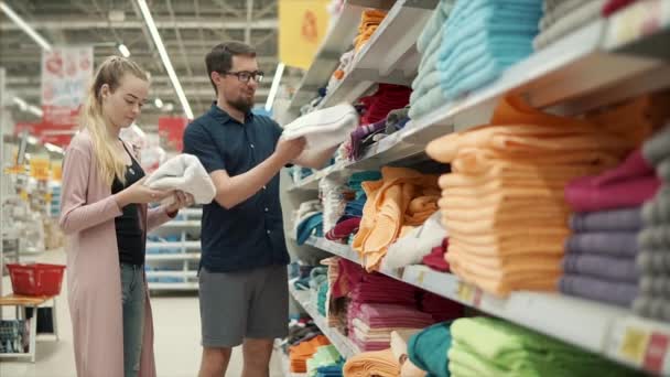 Супруги решают, какой цвет полотенец покупать в магазине, рассматривая ассортимент — стоковое видео