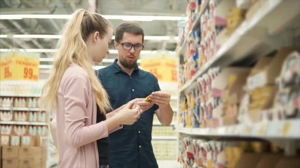 Família jovem comprando alimentos para animais de estimação no supermercado . — Vídeo de Stock