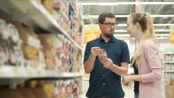 Cheerful couple is choosing forage for their domestic cat in a supermarket — Stock Video