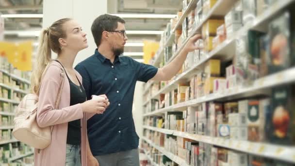 Los cónyuges están de compras en una tienda de comestibles, la elección de té envasado — Vídeo de stock