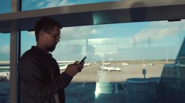 Ciddi adam Havaalanı salonunda ayakta, Smartphone mesajlar okuyor