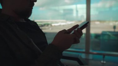 Adam havaalanında oturan cep telefonu sensör ekranında kaydırarak olduğunu, yakın çekim