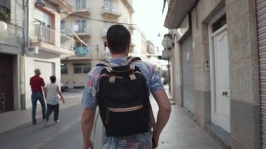Adam küçük kasabada eski caddelerde seyahat ediyor, etrafa bakıyor