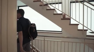 Adam merdivene giriyor, düz kapıya yaklaşıyor, manyetik anahtar uyguluyor