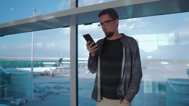 Ung man använder gratis WiFi via smartphone i ett väntrum på flyg platsen — Stockvideo