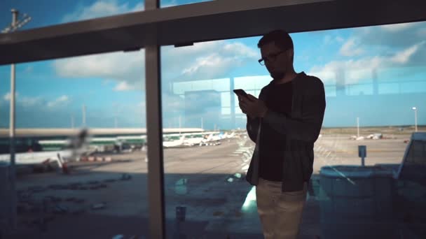 Touriste en vêtements décontractés à l'aéroport avec smartphone . — Video