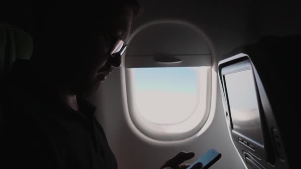 Empresario está utilizando teléfono inteligente en una cabina de aviones durante el vuelo — Vídeos de Stock