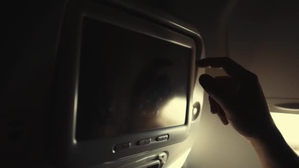 El hombre está presionando botones en una pantalla táctil en una silla en cabina de avión — Vídeos de Stock