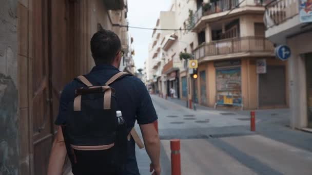 Männlicher Stadtbewohner läuft tagsüber in schmaler Gasse mit kleinen Kreuzungen — Stockvideo