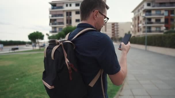 Turista masculino adulto está navegando en la zona de la ciudad utilizando un teléfono inteligente moderno con mapas — Vídeos de Stock