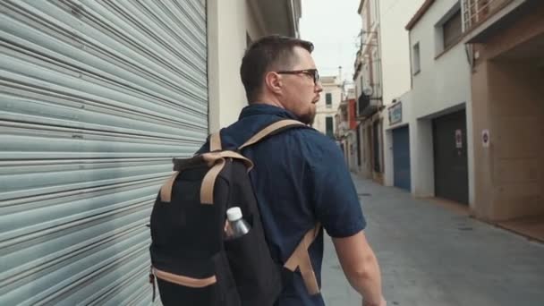 Ensam man går på smala stads gatan, ser sig omkring, tillbaka vy — Stockvideo