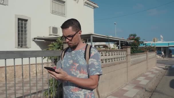 Adulto hombre serio está caminando en la calle con teléfono inteligente en las manos, vista frontal — Vídeo de stock