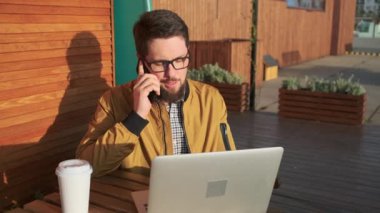 Telefonda konuşurken laptop açık adam.