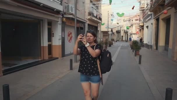 Mujer está de pie en la vieja calle de la ciudad y tomar fotos de lugares de interés — Vídeo de stock