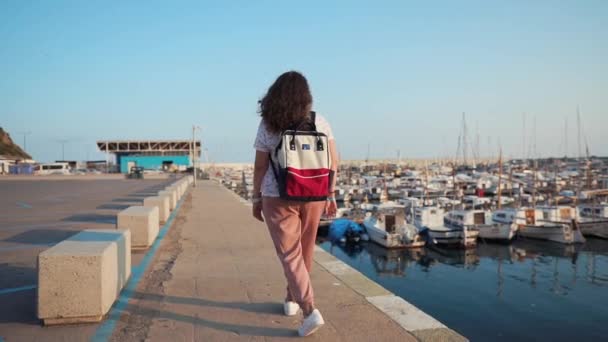 Woman is strolling alone on sea pearce with many private boats in morning time — Stock Video