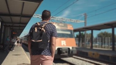 Banliyö treni bir istasyona geliyor, insanlar yatılı hazırlanıyor