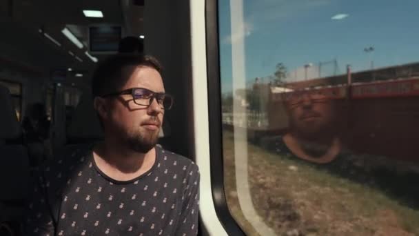 Knappe baard man zit in een wagon van de lokale trein en op zoek in Window — Stockvideo