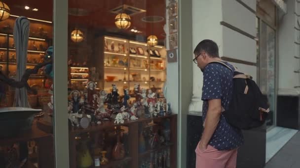 Man is het bekijken van een showcase van Souvenirwinkel in de oude toeristische stad in de zomer dag — Stockvideo