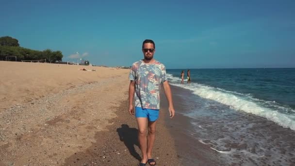 Чоловік випадково гуляє на пляжі влітку . — стокове відео