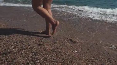 Kadın güneşli bir gün bir deniz kıyısında yalnız gezinen, bacaklarını yakın çekim