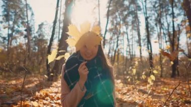 Güzel kız el akçaağaç bırakmak ile oynuyor, Güz ormanda oturan