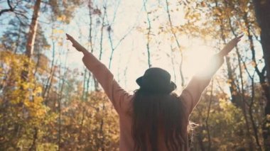 Genç esmer kız sonbahar ormanda yalnız ayakta ve ellerini kaldırma, geri