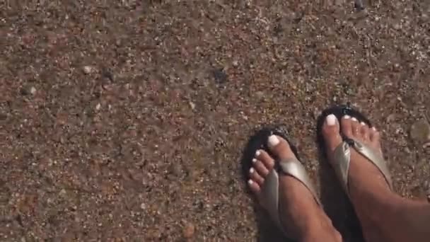 Vrouw staat in het water van de warme zee, close-up van haar voeten en schoenen, bovenaanzicht — Stockvideo