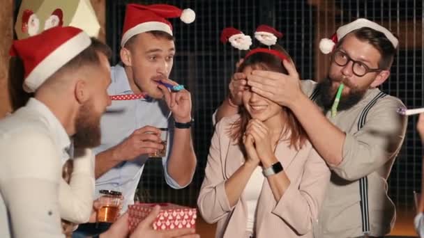 友人は、クリスマスパーティーに手で彼女の目を閉じて、女性のための贈り物を与えている — ストック動画