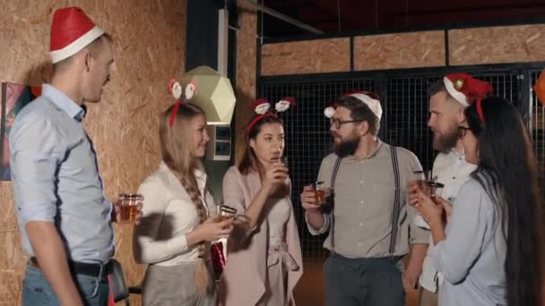 Радующиеся юные друзья болтают и пьют на рождественской вечеринке — стоковое видео
