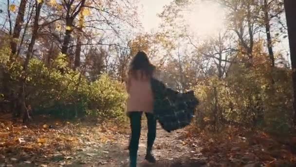 Mujer joven asustada está corriendo en el camino en el bosque de otoño en el día, vista de atrás — Vídeo de stock