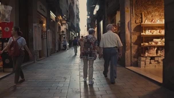 Barcelona, Hiszpania-wrzesień 2018: deptak w dzielnicy gotyckiej. Para seniorów spacerów wzdłuż sklepów z pamiątkami w ciągu dnia — Wideo stockowe