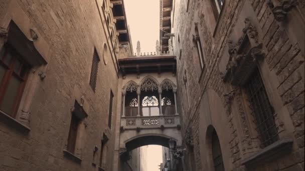 Barcelona, Španělsko-září 2018: Most polibků na ulici Carrer del Bisbe, Biskupská ulice, uprostřed gotické čtvrti. Naklánět pohled na nádherný architektonický orientační bod. — Stock video
