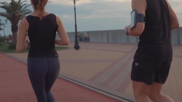 Man och kvinna springer över vägen utomhus, närbild på benen från ryggen — Stockvideo