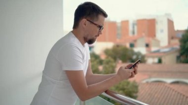 Balkonda cep telefonu ile güzel adam.