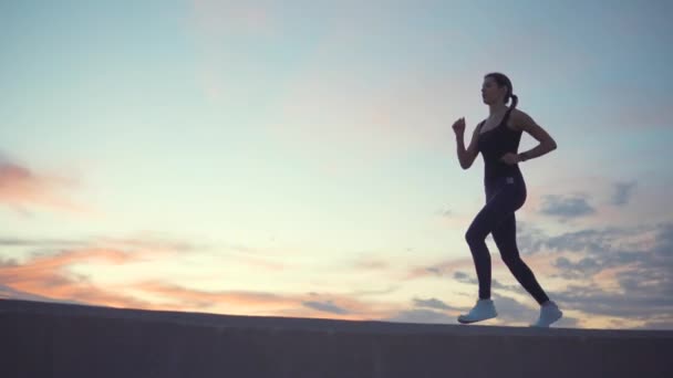 Ung kvinna springer, figur mot molnigt himmel i solnedgången tid — Stockvideo