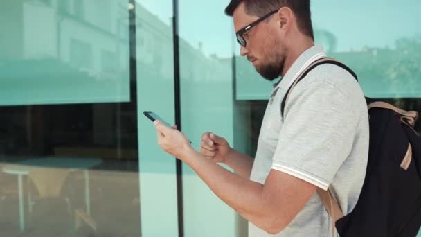 Hombre sosteniendo el teléfono inteligente mientras camina . — Vídeo de stock