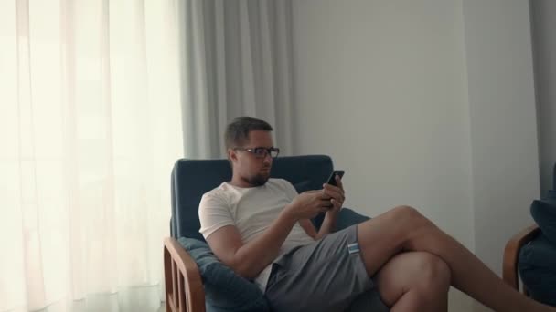 Man in de stoel surfen web op smartphone. — Stockvideo