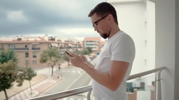 Muž s smartphone na balkóně. — Stock video