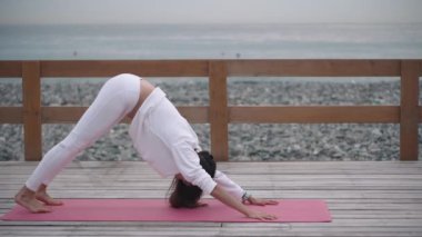 Sportswoman güzel deniz manzarası yakınında yoga pozlar performans