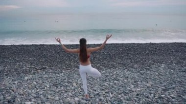 Kadın bir bacak üzerinde ayakta ve gündüz önünde deniz meditasyon